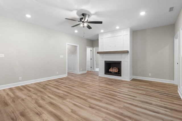 unfurnished living room with ceiling fan, a fireplace, and light hardwood / wood-style floors