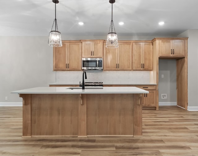 kitchen with sink, decorative light fixtures, and a kitchen island with sink