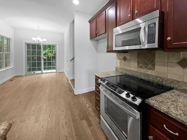 3047 Dogwood Trl, Spring Hill, TN 37174 - kitchen with stainless steel appliances, reddish brown cabinets, a chandelier, baseboards, and recessed lighting