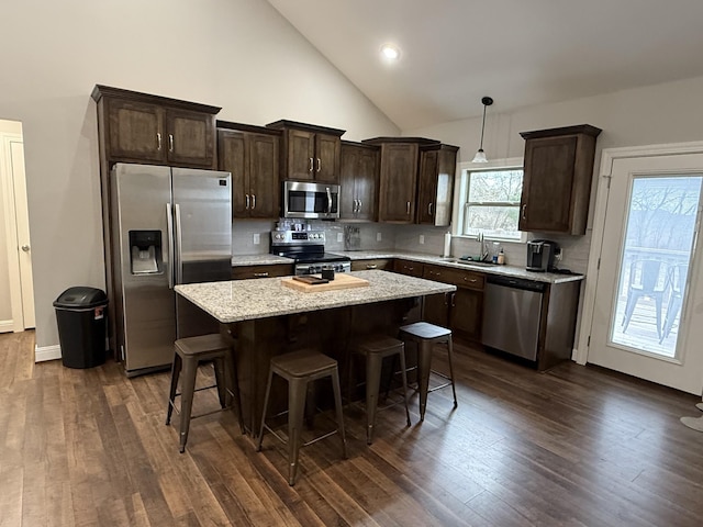 kitchen featuring a kitchen island, sink, dark hardwood / wood-style flooring, hanging light fixtures, and stainless steel appliances