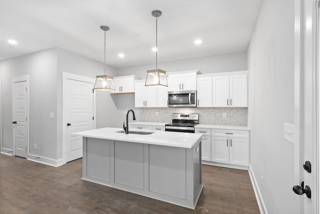 kitchen with an island with sink, appliances with stainless steel finishes, white cabinets, and decorative light fixtures