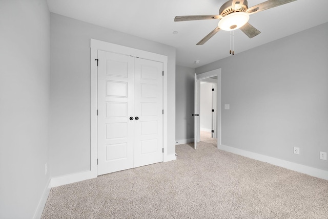 unfurnished bedroom with light colored carpet, ceiling fan, and a closet