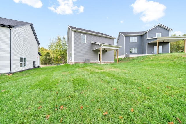 rear view of house with central AC unit and a lawn