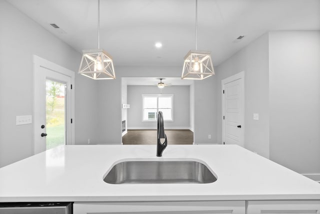 kitchen featuring an island with sink, decorative light fixtures, dishwasher, and sink