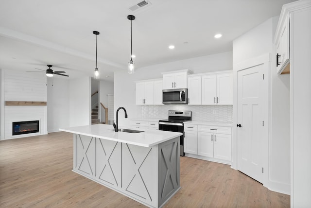 kitchen with pendant lighting, sink, white cabinetry, a kitchen island with sink, and stainless steel appliances