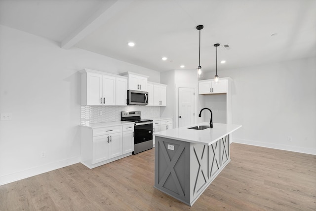 kitchen with stainless steel appliances, white cabinetry, sink, and a center island with sink