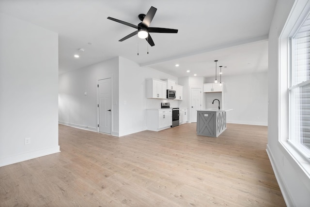 unfurnished living room with ceiling fan, sink, and light hardwood / wood-style floors