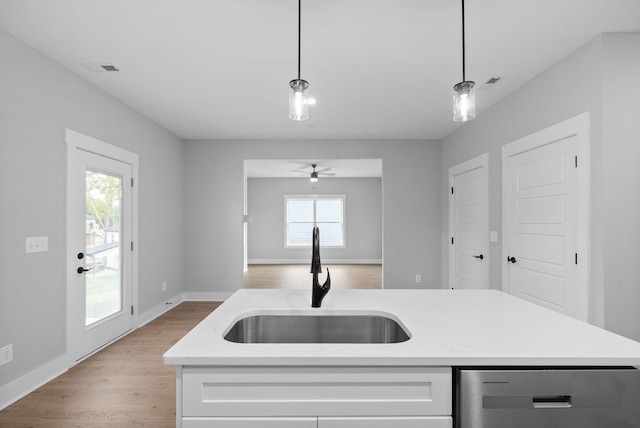 kitchen featuring sink, hanging light fixtures, light hardwood / wood-style floors, a center island with sink, and stainless steel dishwasher