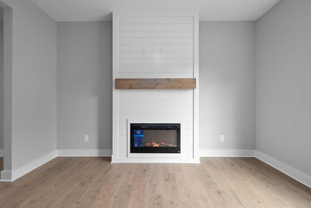 unfurnished living room featuring a large fireplace and light hardwood / wood-style floors