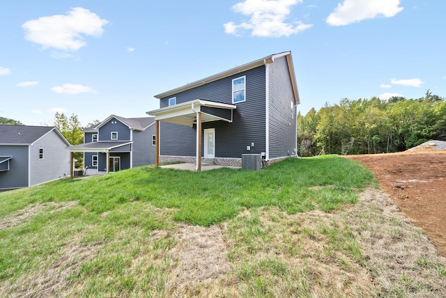 rear view of house featuring central AC unit and a lawn