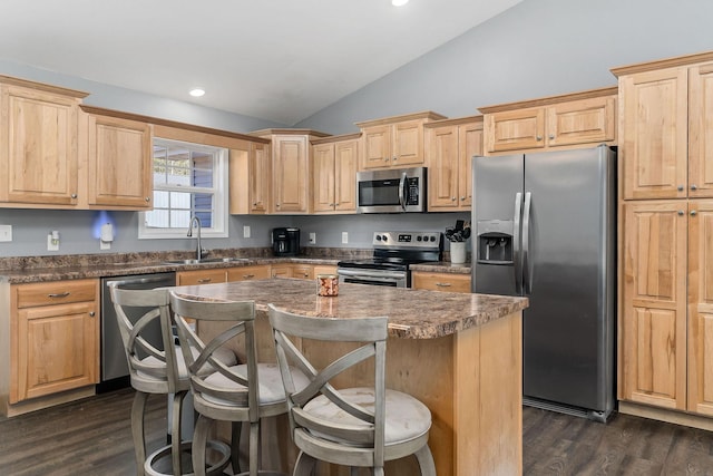 kitchen featuring lofted ceiling, sink, stainless steel appliances, a kitchen breakfast bar, and a kitchen island