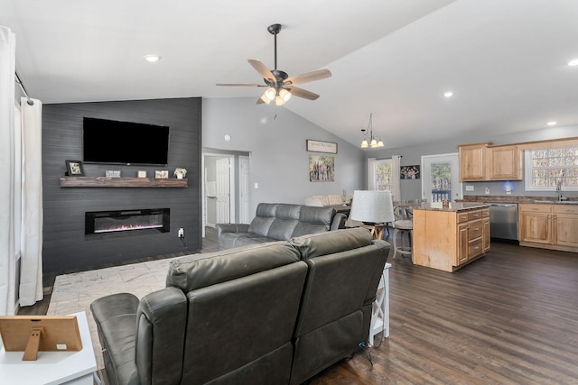 living room with ceiling fan with notable chandelier, lofted ceiling, a large fireplace, sink, and dark hardwood / wood-style flooring