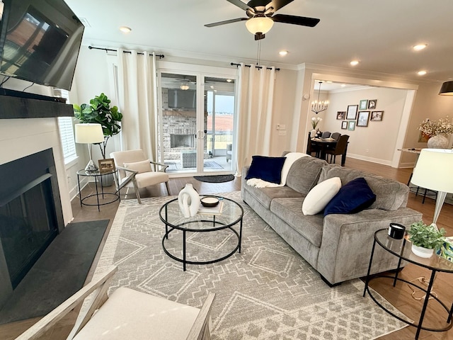 living room featuring crown molding, ceiling fan with notable chandelier, and hardwood / wood-style floors