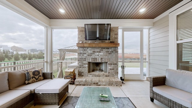 sunroom featuring a brick fireplace and wooden ceiling