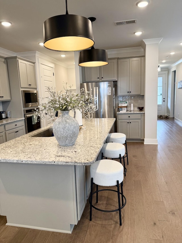 kitchen featuring gray cabinetry, hanging light fixtures, ornamental molding, and appliances with stainless steel finishes