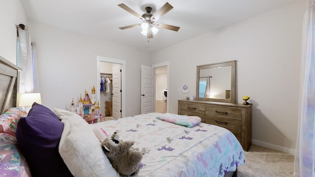 bedroom with a walk in closet, light colored carpet, ceiling fan, and a closet