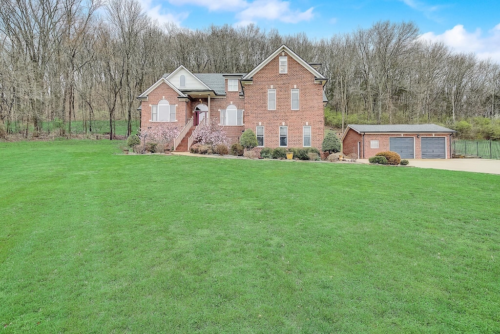 view of front of property with a garage, an outdoor structure, and a front lawn