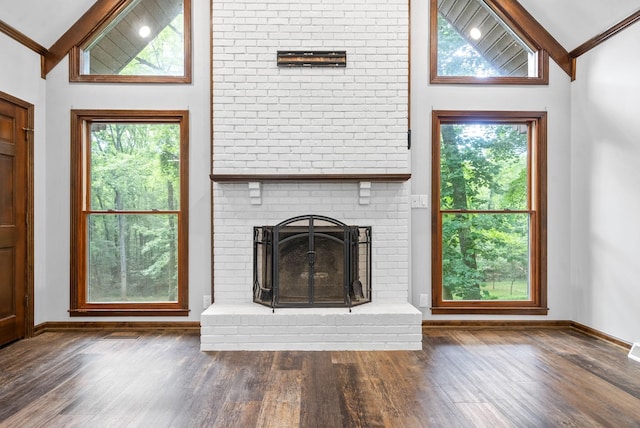 unfurnished living room featuring a fireplace, ornamental molding, dark hardwood / wood-style flooring, and vaulted ceiling with beams