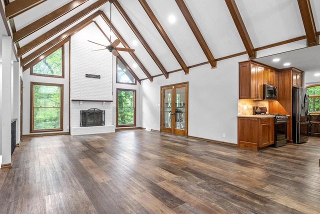 unfurnished living room with plenty of natural light, dark hardwood / wood-style flooring, high vaulted ceiling, and a brick fireplace