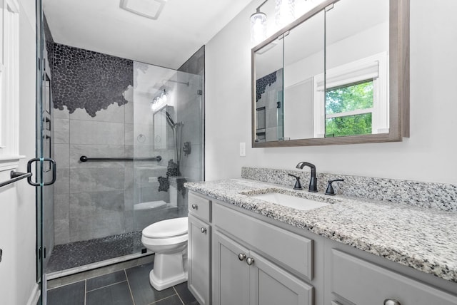 bathroom with tile patterned floors, vanity, toilet, and a shower with shower door