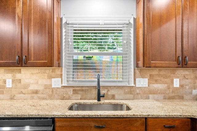 kitchen featuring tasteful backsplash, dishwasher, sink, and light stone counters