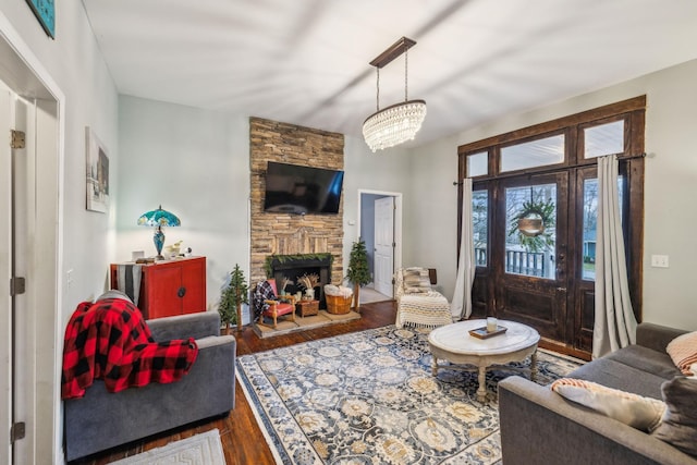 living room featuring wood-type flooring, an inviting chandelier, and a fireplace