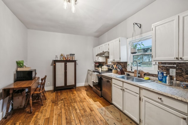 kitchen featuring sink, hardwood / wood-style floors, stainless steel appliances, tasteful backsplash, and white cabinets