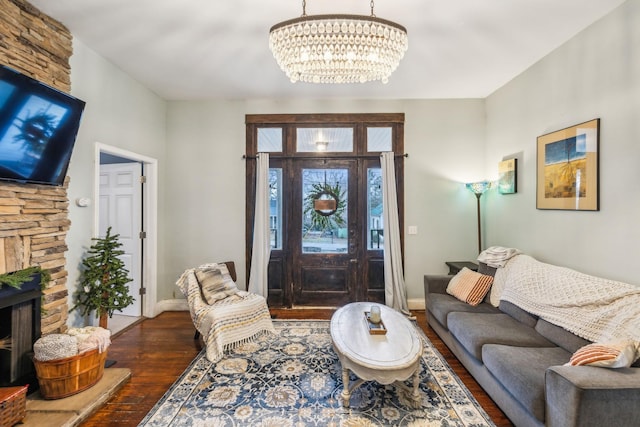 living room with a stone fireplace, a notable chandelier, and dark hardwood / wood-style flooring