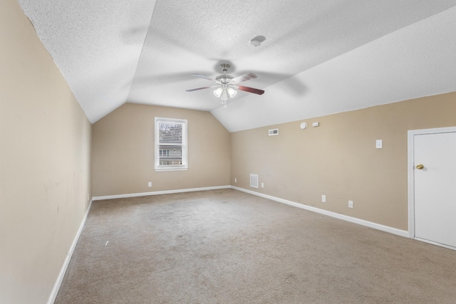 bonus room with lofted ceiling, light colored carpet, a textured ceiling, and ceiling fan