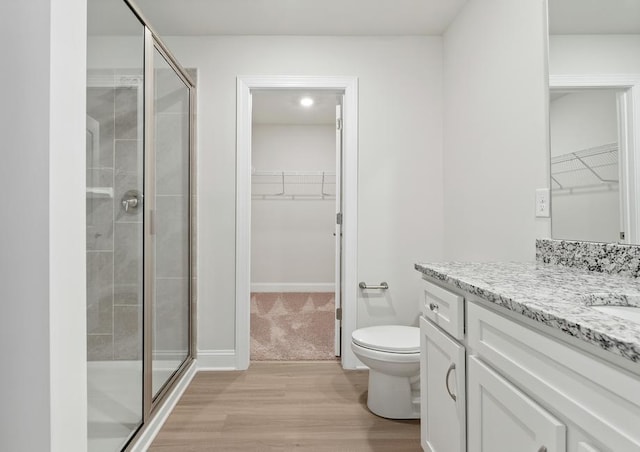 bathroom with vanity, a shower with shower door, toilet, and wood-type flooring