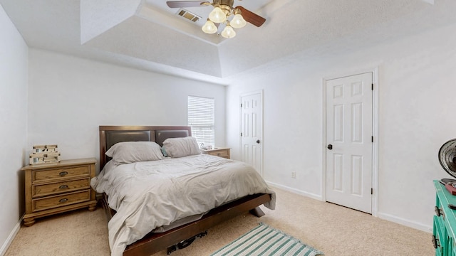 bedroom with baseboards, visible vents, a raised ceiling, and light colored carpet