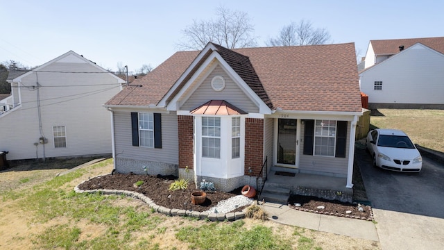 view of front facade featuring brick siding, driveway, and roof with shingles