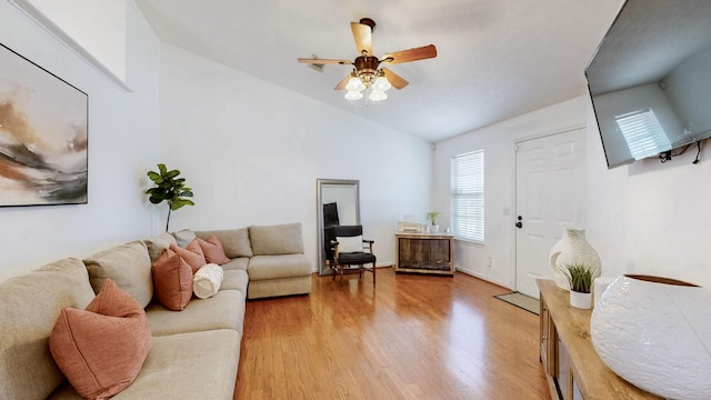 living area with light wood-type flooring, vaulted ceiling, and a ceiling fan