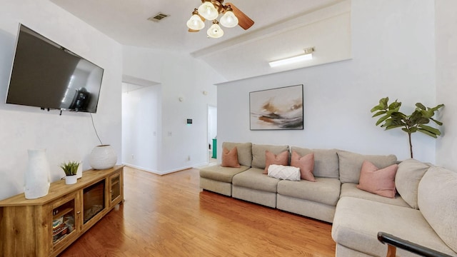 living area featuring baseboards, visible vents, a ceiling fan, wood finished floors, and vaulted ceiling