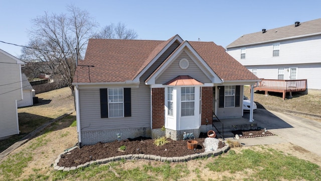 view of front of house with driveway, a shingled roof, a patio, and brick siding