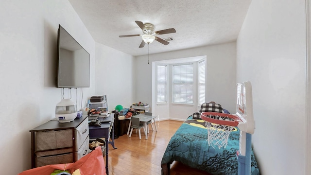 bedroom featuring visible vents, baseboards, ceiling fan, a textured ceiling, and light wood-type flooring