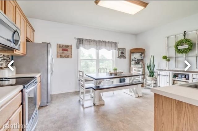 kitchen featuring appliances with stainless steel finishes, backsplash, and light brown cabinetry