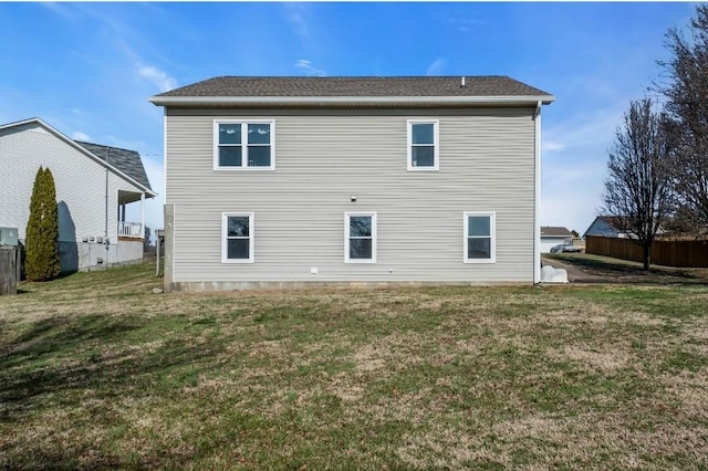 rear view of house with a yard and fence