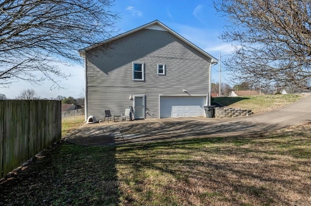 back of property featuring a yard, driveway, a garage, and fence