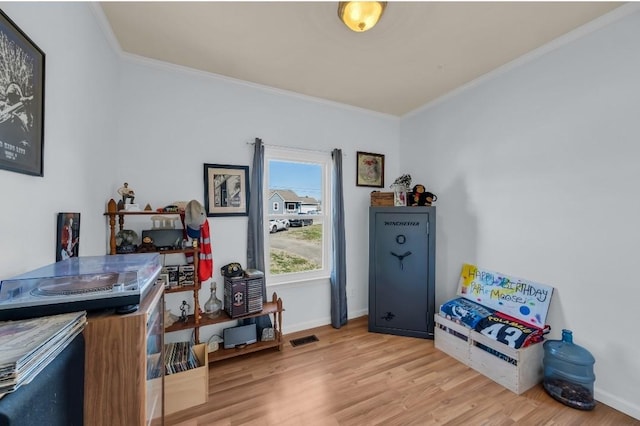 interior space with visible vents, crown molding, baseboards, and wood finished floors