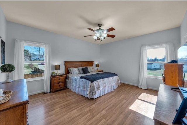 bedroom with light wood finished floors, multiple windows, and baseboards