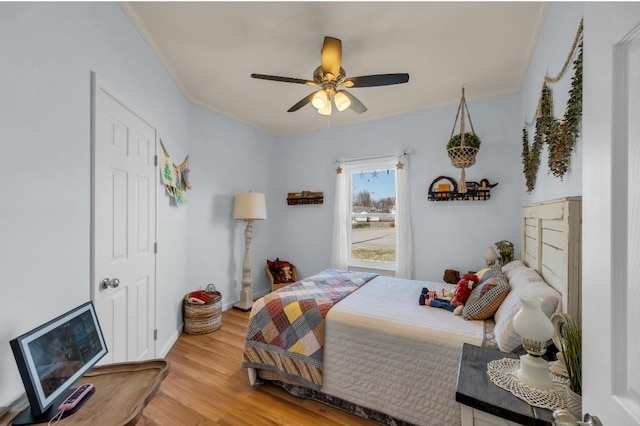 bedroom featuring ceiling fan, ornamental molding, and light wood finished floors