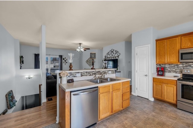 kitchen with backsplash, open floor plan, light countertops, stainless steel appliances, and a sink