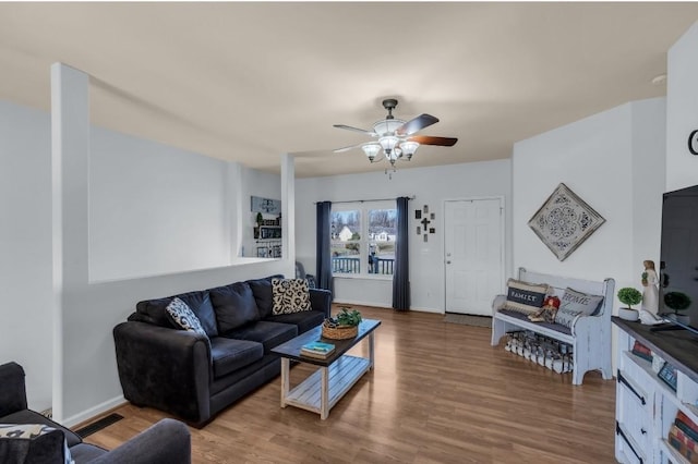 living area with ceiling fan, visible vents, baseboards, and wood finished floors