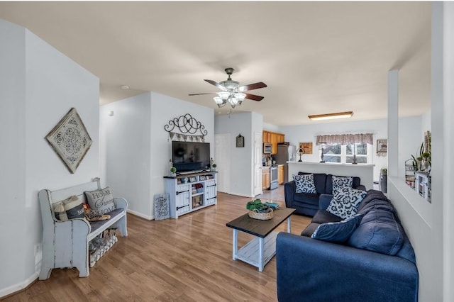 living area with light wood finished floors, baseboards, and ceiling fan