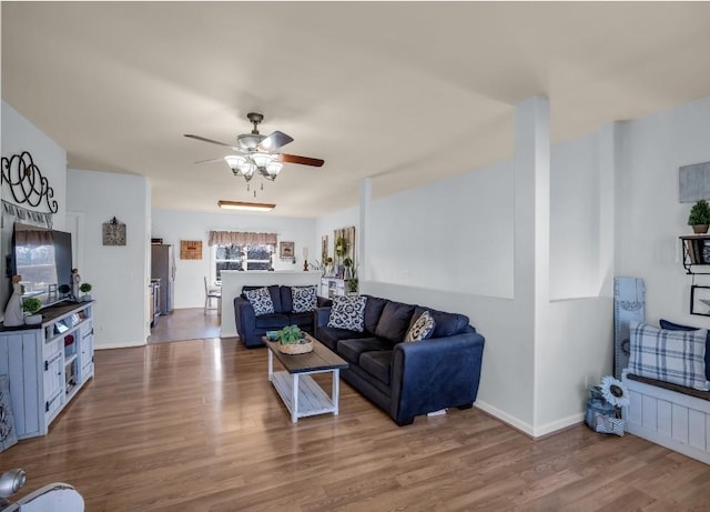 living room featuring baseboards, ceiling fan, and wood finished floors