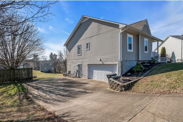 view of property exterior featuring an attached garage, fence, a lawn, and driveway