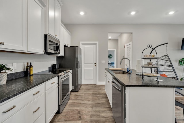 kitchen featuring sink, stainless steel appliances, a kitchen breakfast bar, white cabinets, and a center island with sink