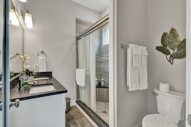 bathroom with a shower with door, vanity, hardwood / wood-style floors, and toilet