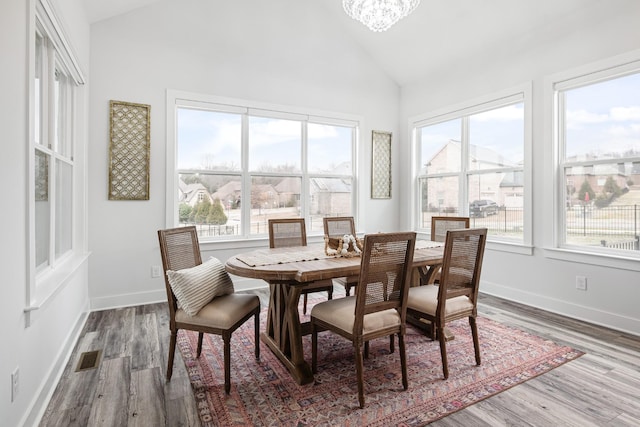 dining room featuring a notable chandelier, wood-type flooring, and high vaulted ceiling